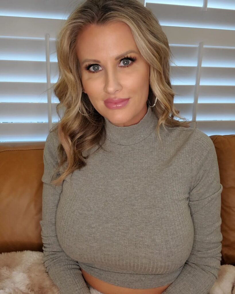 Only Andi of onlyandi onlyfans of blonde milf model sexy kneeling pose with big tits by sofa. Alluring expression lady sexy kneeing.